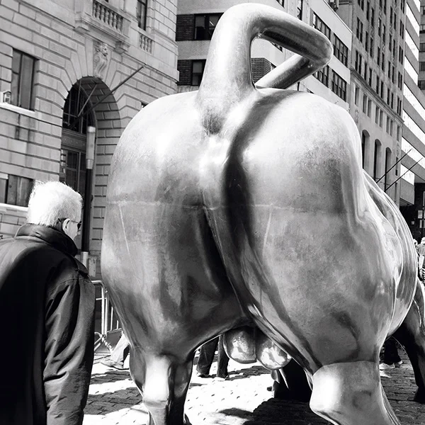 Artistic street photography of a man in front of the Charging Bull in New York.