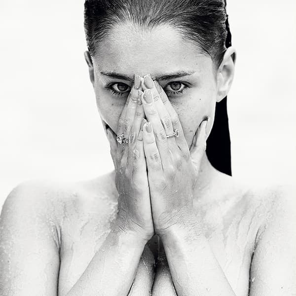Erotische Schwarzweiß-Fotografie einer nassen Frau mit intensivem Blick, verdecktem Gesicht und sichtbarem Oberkörper – limitierte fine art aktfotografie