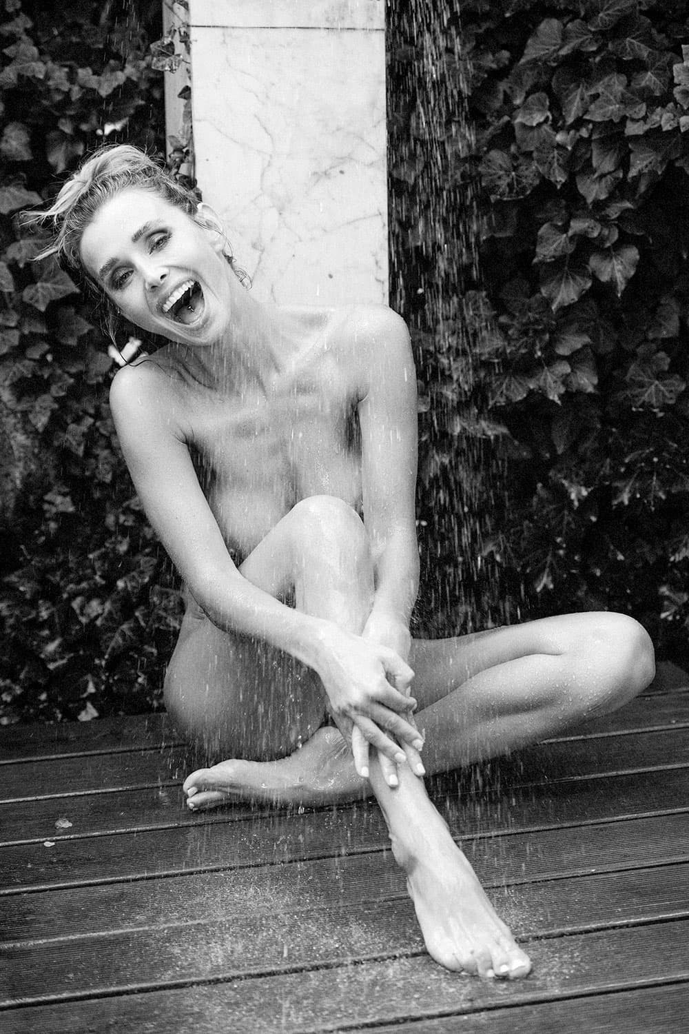 „Garden Hose Baptism“ – Schwarzweiß-Akt im Außenbereich unter Wasserstrahl, spielerisch und roh – limitierte fine art aktfotografie