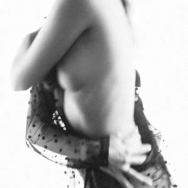 Erotische Fotografie mit Unschärfe, die eine sinnliche Pose in einem zarten Moment einfängt, mit Fokus auf Bewegungen und Licht.