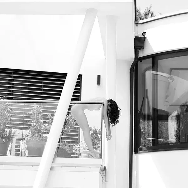Erotische Aktfotografie in minimalistischer Architektur – eine Frau hängt über dem Geländer, zwischen Kontrolle und Absturz.