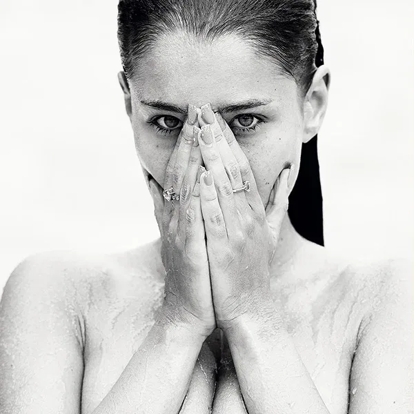 Erotische Schwarzweiß-Fotografie einer nassen Frau mit intensivem Blick, verdecktem Gesicht und sichtbarem Oberkörper – limitierte fine art aktfotografie
