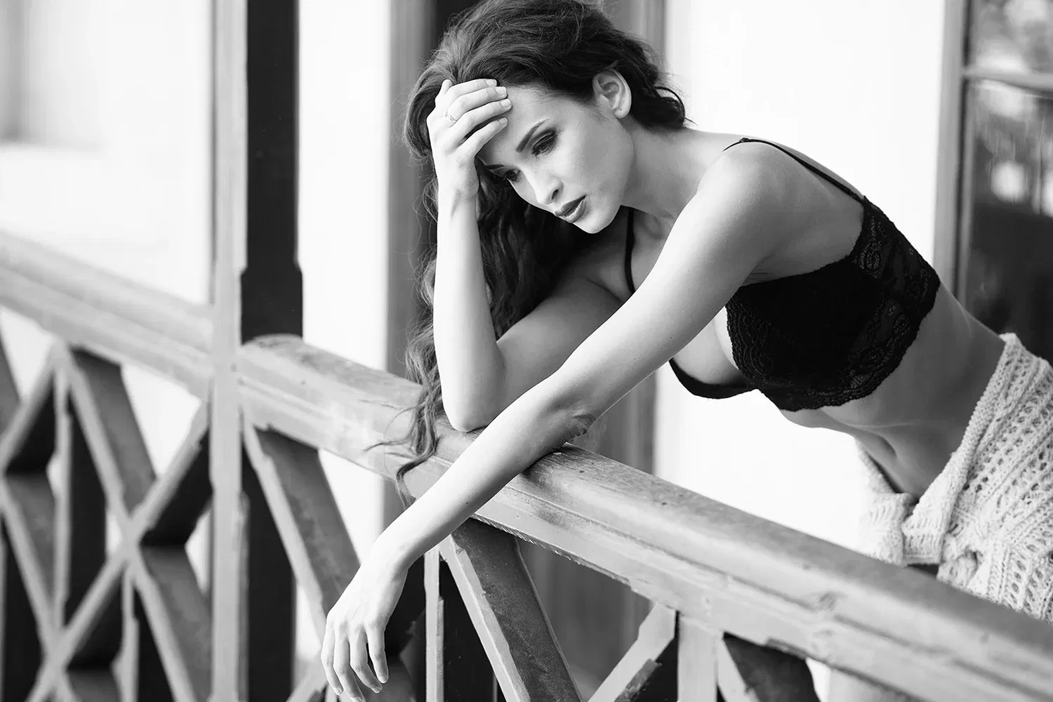 Schwarz-weiß Foto einer Frau auf einem Balkon in nachdenklicher Pose; künstlerische Fotografie, die häufig von KI Zensur fälschlich blockiert wird.